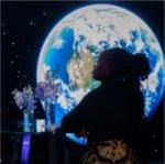 A visitor to GVSU's "The Blue Dot Experience," event is silhouetted against an image of the Earth.